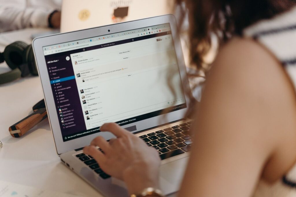 Mastering the First Impression: Your intriguing post title goes here A businesswoman typing on a laptop in an office setting, using Slack for communication.
